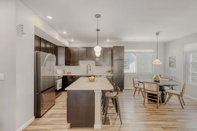 a open kitchen with stainless steel appliances kitchen island granite countertop a table chairs and a refrigerator