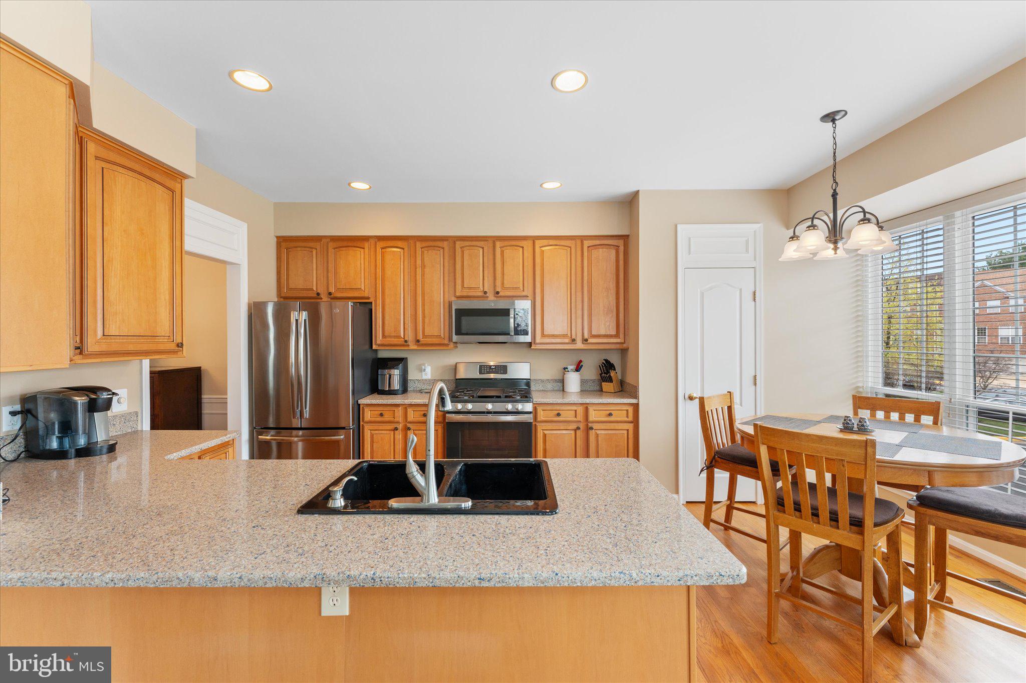 20900 Trinity Square Sterling, VA 20165 - Photo 4 of 46 a kitchen with stainless steel appliances granite countertop a refrigerator a stove a sink a dining table and chairs with wooden floor
