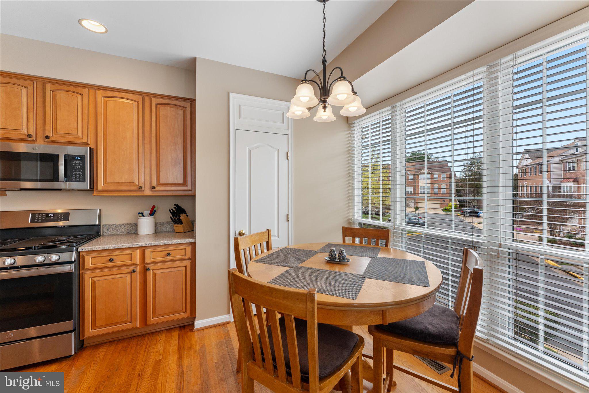 20900 Trinity Square Sterling, VA 20165 - Photo 7 of 46 a kitchen with stainless steel appliances granite countertop a kitchen island hardwood floor sink stove dining table and chairs