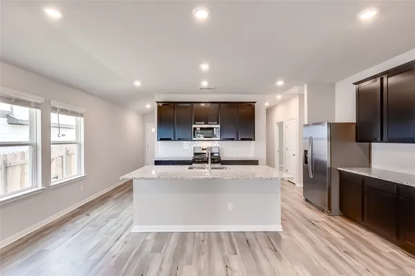 a large kitchen with stainless steel appliances a large counter top and a wooden floors