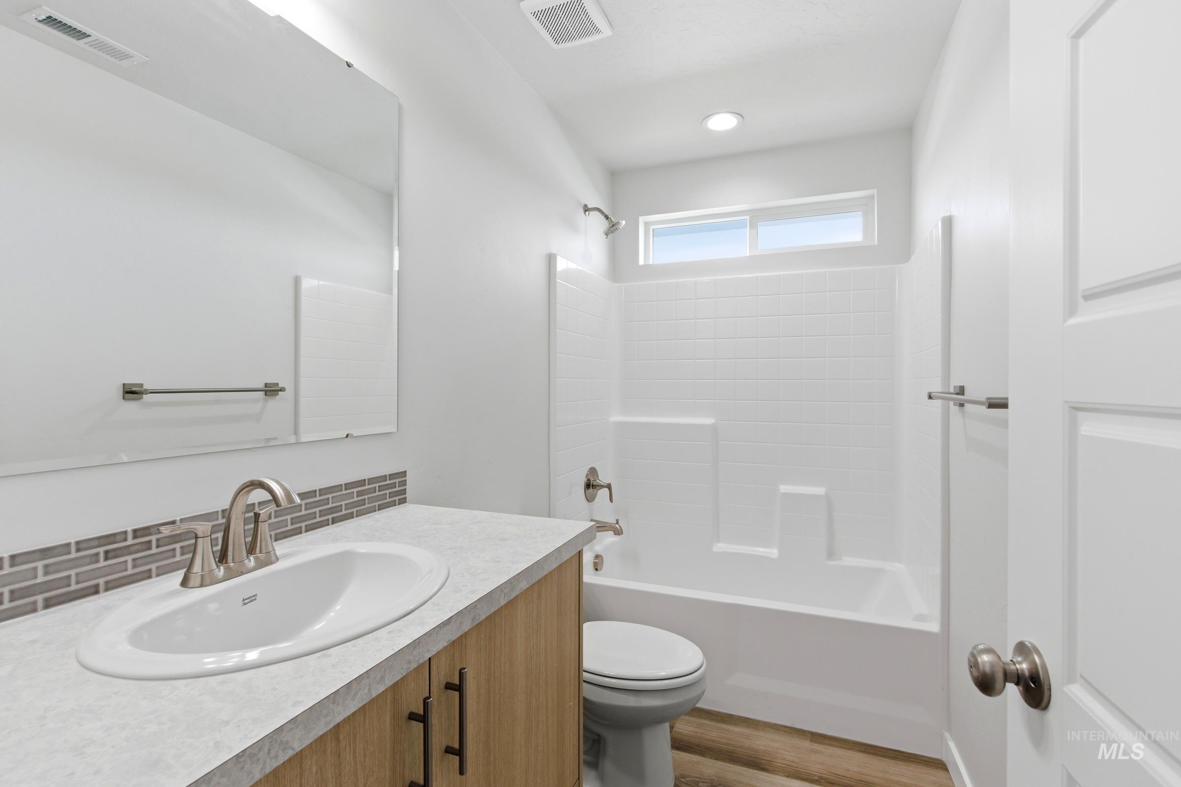 8317 South Tyrion Way Kuna, ID 83634 - Photo 14 of 22 Bathroom featuring a wood-finish vanity with a single basin sink and brushed nickel hardware, complemented by a mosaic tile backsplash