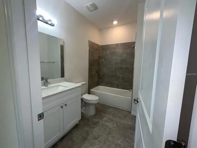 a bathroom with a granite countertop sink a toilet and shower