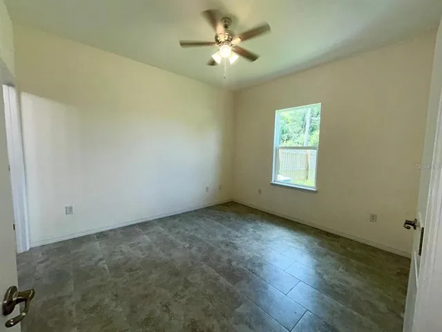 an empty room with a window and a fan