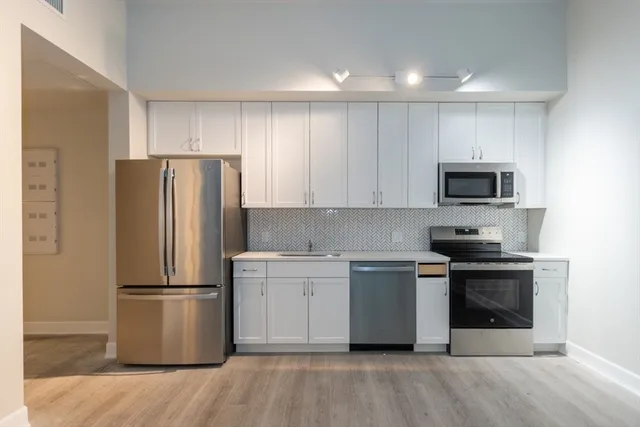 a kitchen with a stainless steel appliances and wooden floor