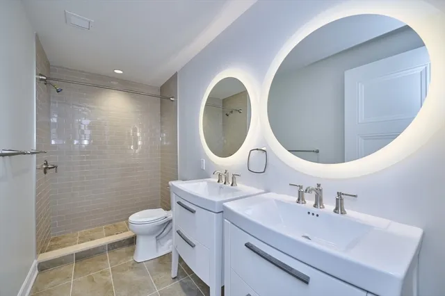 a bathroom with a double vanity sink mirror and toilet