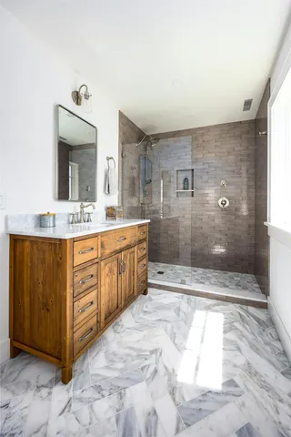 a bathroom with a sink a toilet a mirror and shower