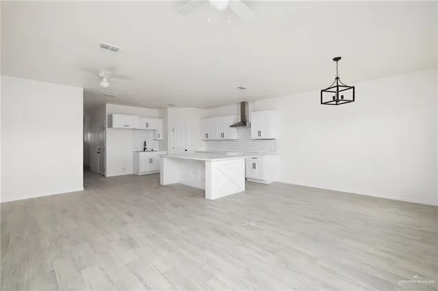 a big room with chandelier and kitchen view