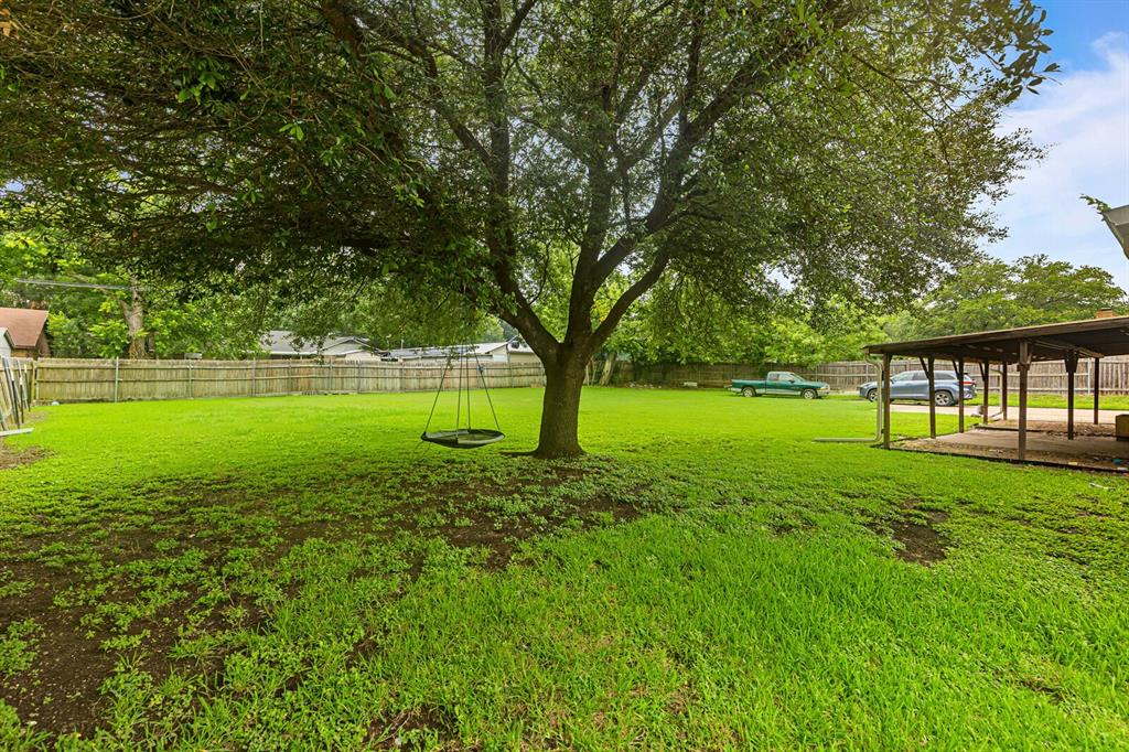 505 Pinewood Lane Hewitt, TX 76643 - Photo 28 of 38 Expansive green lawn featuring a mature shade tree, a wooden privacy fence, and a covered patio structure