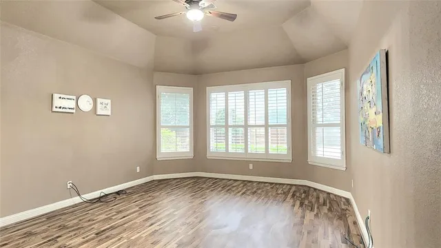 a view of an empty room with a window and wooden floor