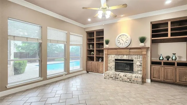 a view of a livingroom with a fireplace a ceiling fan and windows