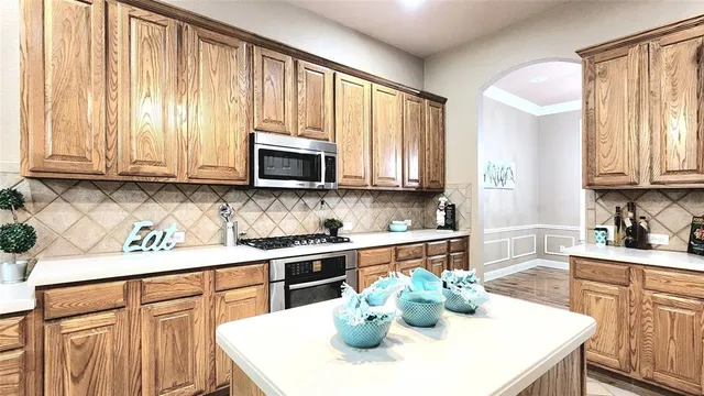 a kitchen with stainless steel appliances kitchen island granite countertop a sink a stove a microwave and dining table