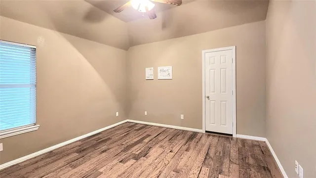 a view of an empty room with wooden floor and a window