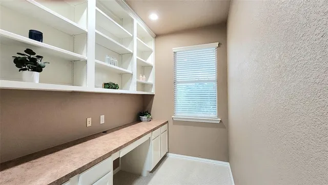 a room with a bookshelf and white cabinets