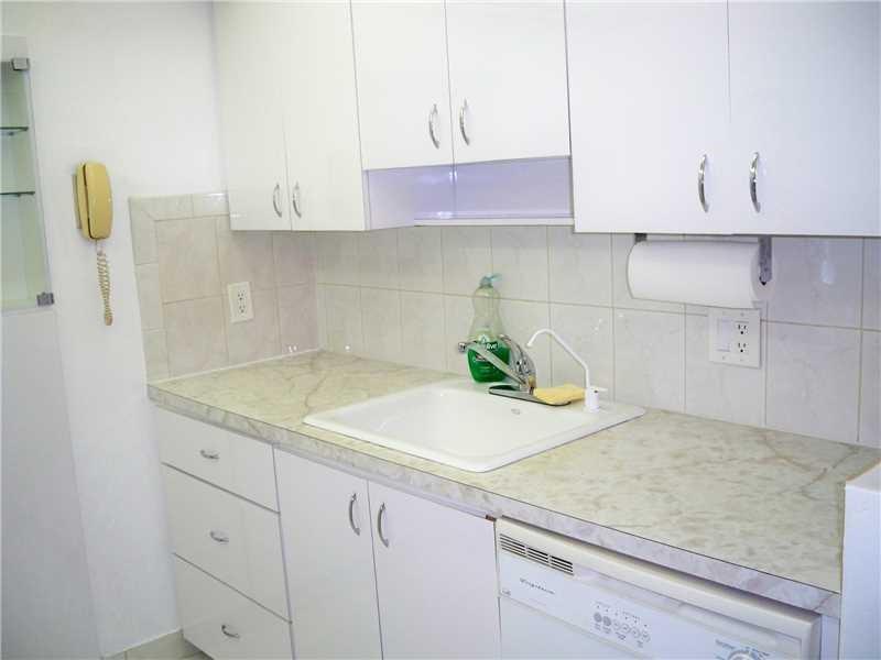 111 Briny Avenue, Unit 806 Pompano Beach, FL 33062 - Photo 6 of 40 a kitchen with granite countertop white cabinets and white appliances