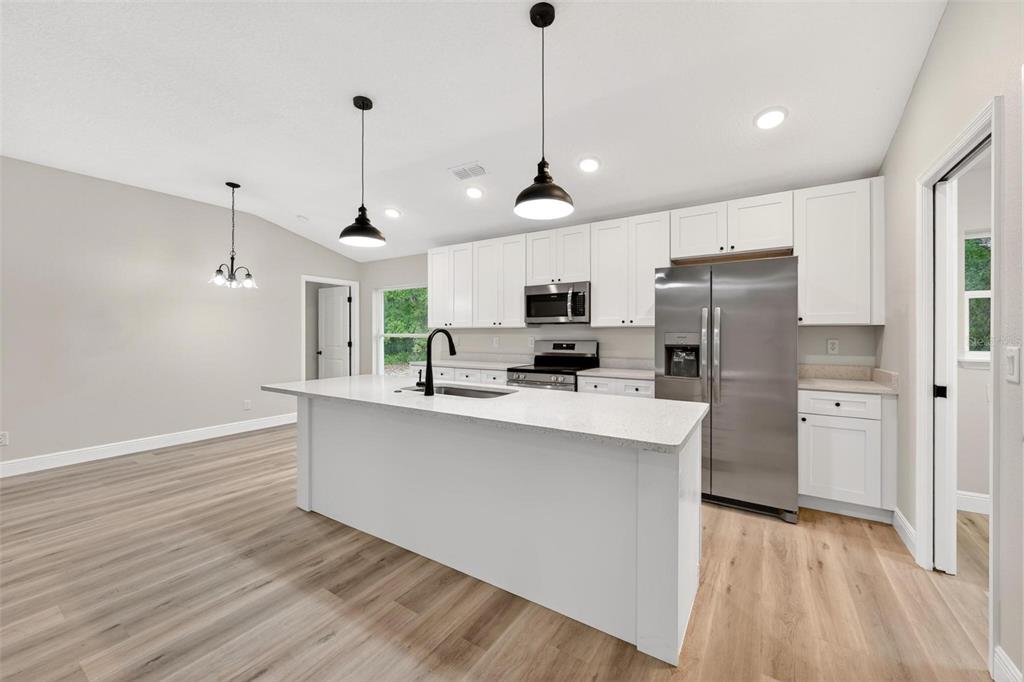 2132 Pine Meadows Golf Course Road Eustis, FL 32726 - Photo 11 of 62 a kitchen with stainless steel appliances a refrigerator a sink dishwasher a oven and white cabinets with wooden floor