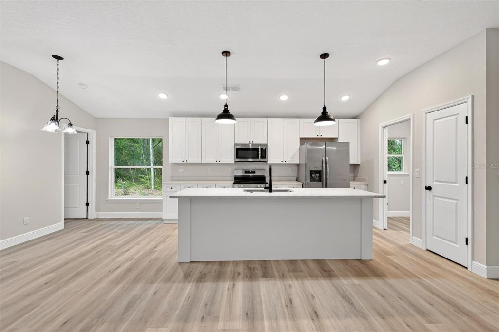2132 Pine Meadows Golf Course Road Eustis, FL 32726 - Photo 7 of 62 a kitchen with stainless steel appliances granite countertop a refrigerator a sink dishwasher a oven and a dining table with wooden floor