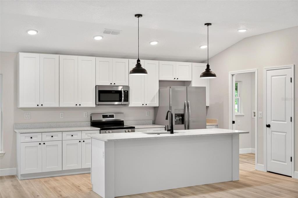2132 Pine Meadows Golf Course Road Eustis, FL 32726 - Photo 8 of 62 a kitchen with stainless steel appliances kitchen island sink refrigerator and microwave