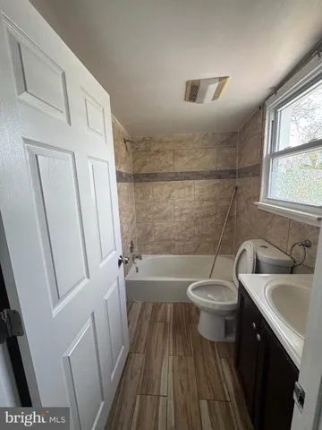 a bathroom with a sink a toilet a window and shower