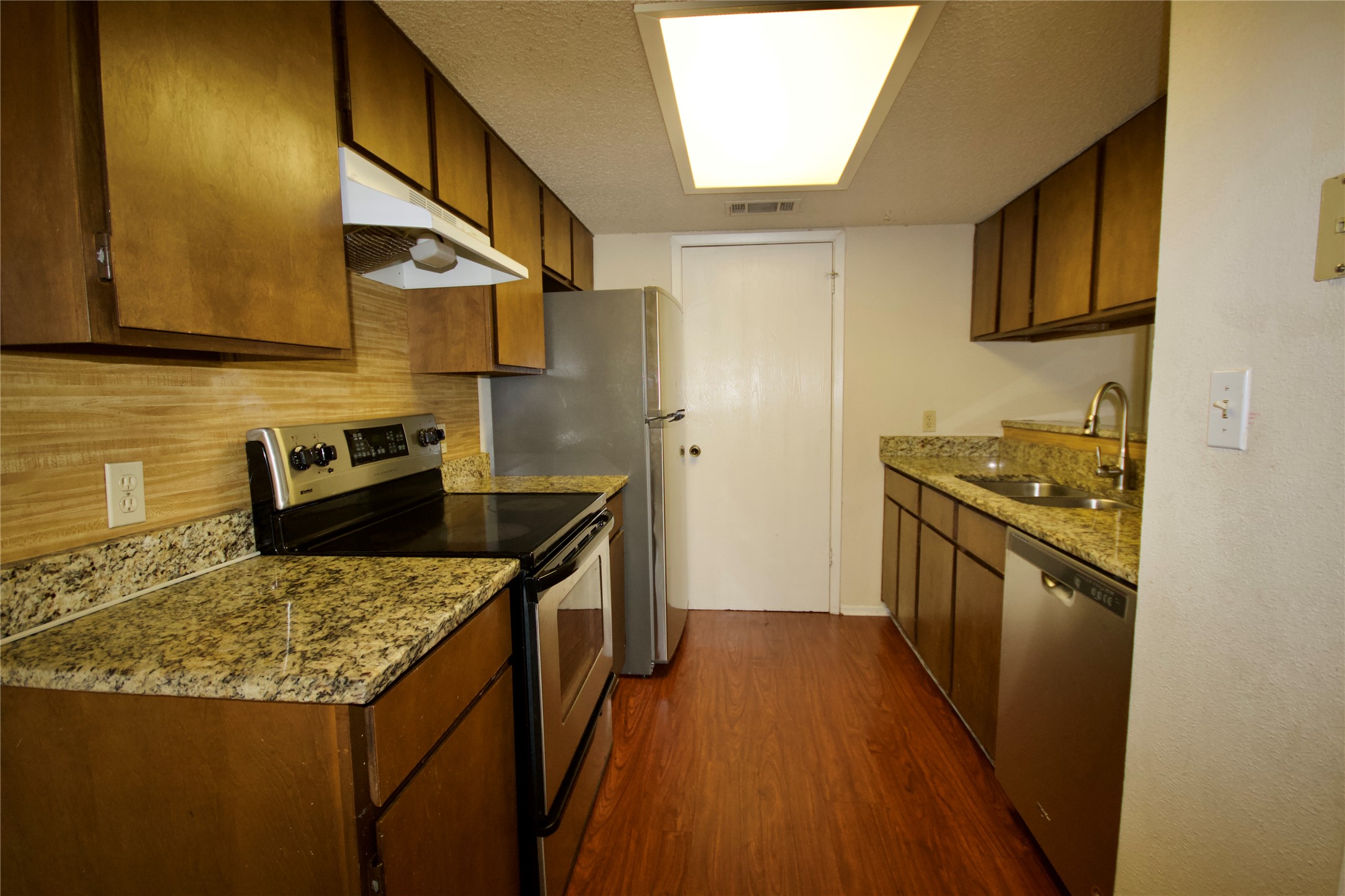 1405 D Camp Craft Road, Unit D West Lake Hills, TX 78746 - Photo 6 of 9 Kitchen with stainless steel appliances, wood finish cabinets, dark wood-style flooring, and light stone counters