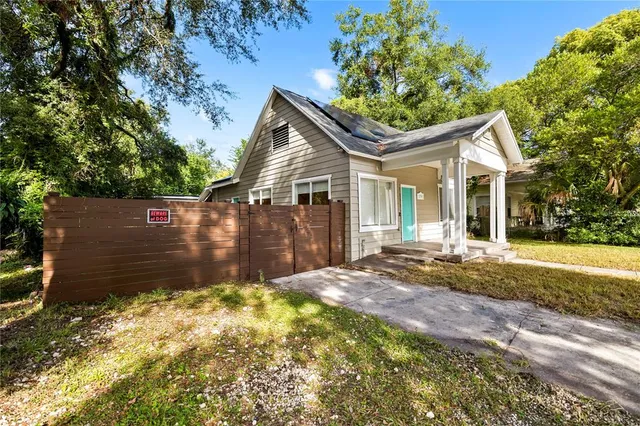 a view of a house with a small yard plants and large tree
