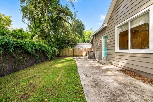 a backyard of a house with plants and large tree