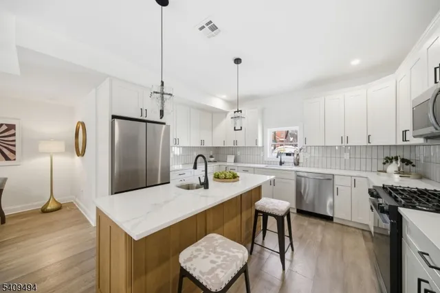 a kitchen with a refrigerator a sink dishwasher a stove and white cabinets with wooden floor