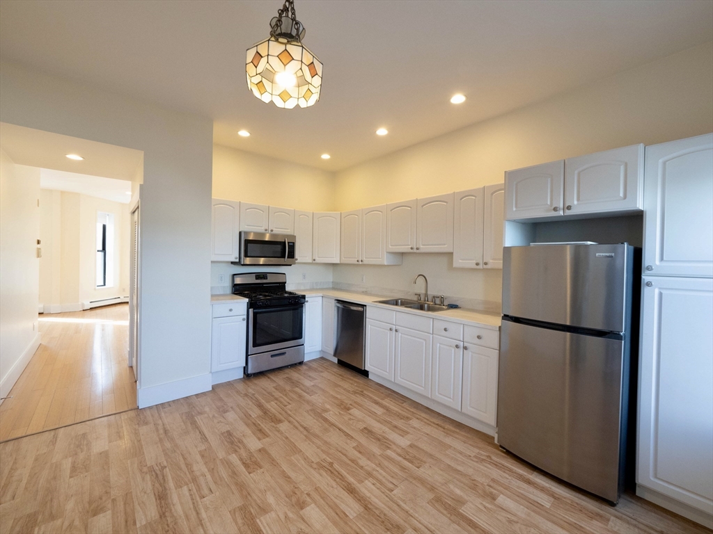 27 Fort Avenue, Unit 2 Boston, MA 02119 - Photo 3 of 7 a kitchen with a refrigerator and a stove top oven