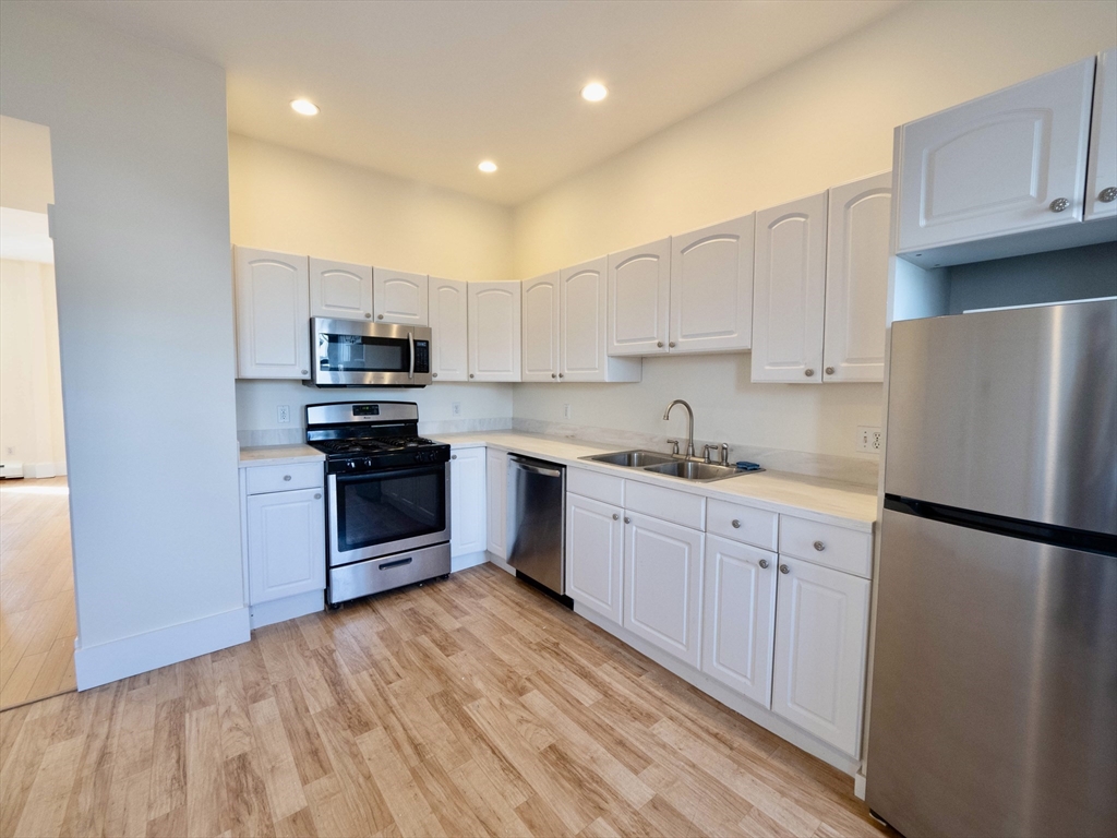 27 Fort Avenue, Unit 2 Boston, MA 02119 - Photo 4 of 7 a kitchen with stainless steel appliances a refrigerator sink and microwave