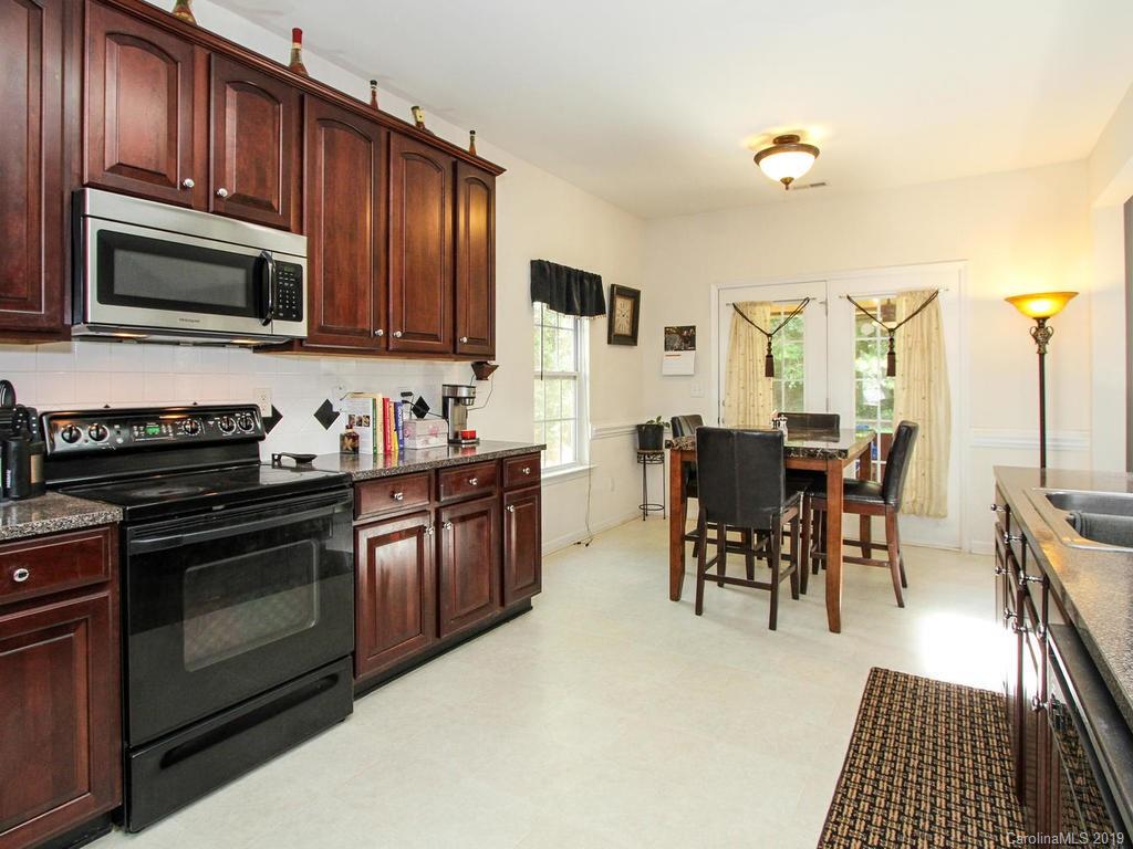 6924 Reedy Creek Road Charlotte, NC 28215 - Photo 15 of 47 a kitchen with stainless steel appliances granite countertop a stove top oven a sink dishwasher a dining table and chairs with wooden floor