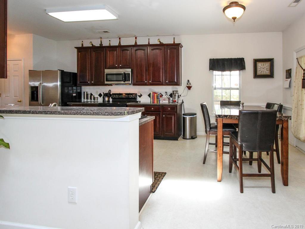 6924 Reedy Creek Road Charlotte, NC 28215 - Photo 19 of 47 a kitchen with stainless steel appliances granite countertop a refrigerator a stove a sink a dining table and chairs