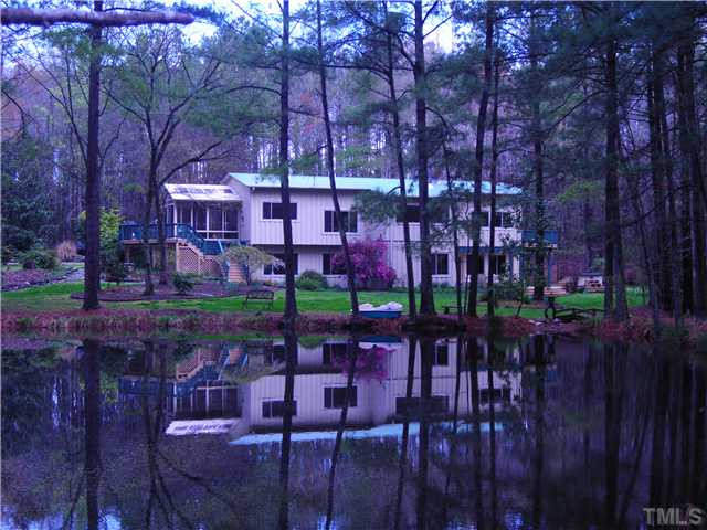 3729 Bosco Road New Hill, NC 27562 - Photo 1 of 25 View of the back of the home reflecting on the pond. Imagine the fun you could have on this beautiful pond. You could take a morning or evening stroll on the pond in your paddle boat. Exterior Back