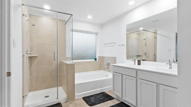 a bathroom with a tub shower sink and mirror