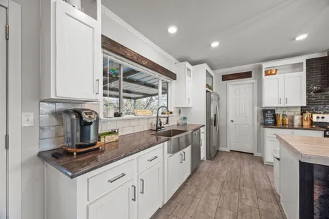 a kitchen with kitchen island a stove a refrigerator and a dining table with wooden floor