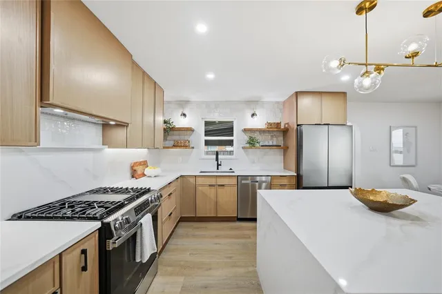 a kitchen with stainless steel appliances granite countertop a sink a stove and refrigerator