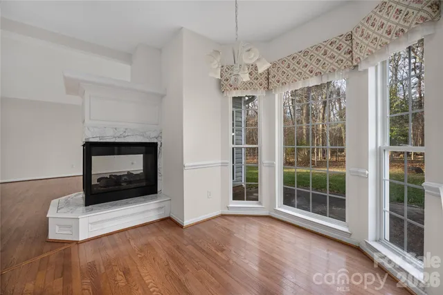 a view of an empty room with wooden floor fireplace and a window