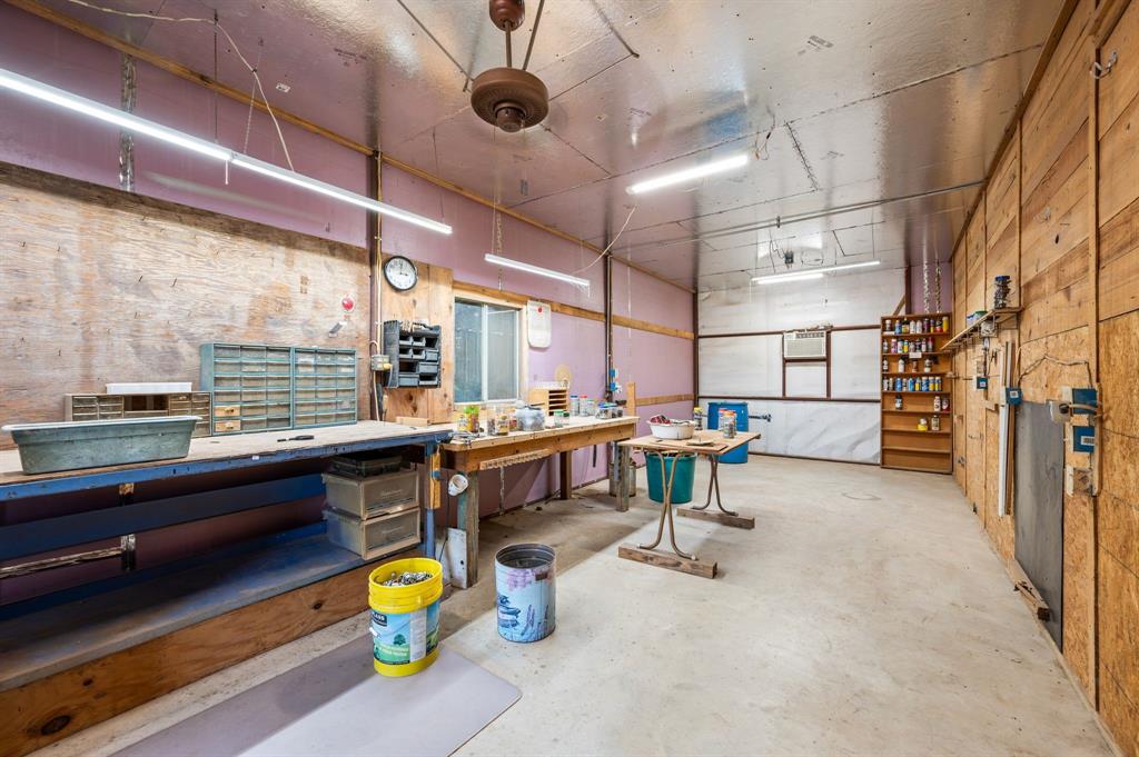 515 New Highland Road Springtown, TX 76082 - Photo 26 of 38 Spacious workshop featuring concrete flooring, expansive workbenches, and built-in shelving