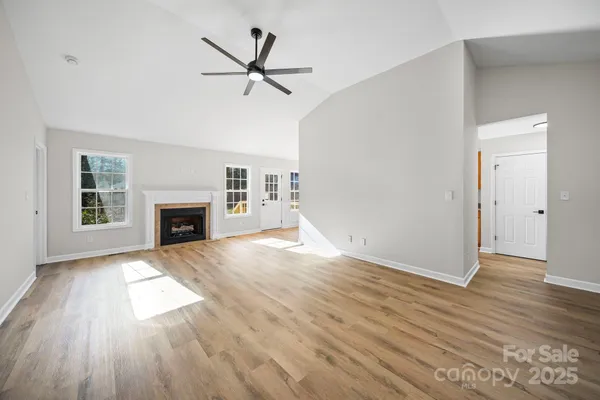 an empty room with wooden floor a ceiling fan and windows