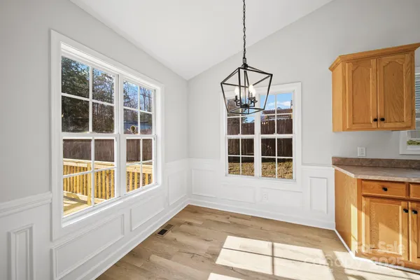 a view of an empty room with a window and chandelier