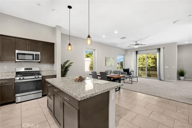 a kitchen with a stove a sink a counter space and living room view