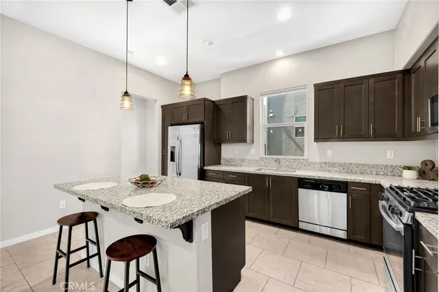 a kitchen with stainless steel appliances granite countertop a sink a stove a refrigerator and island