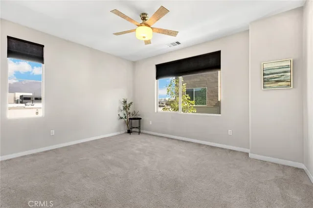 an empty room with windows and fan