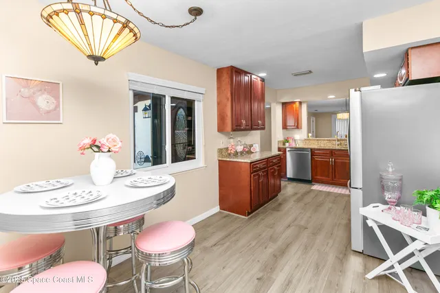 a kitchen with stainless steel appliances kitchen island granite countertop a dining table chairs and a refrigerator