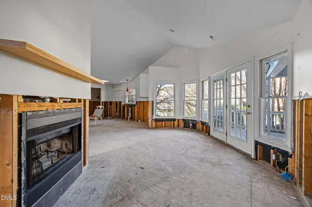 a view of an empty room with fireplace and windows