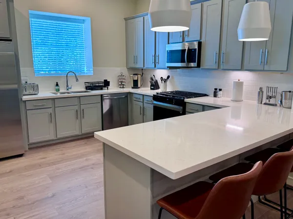 a kitchen with stainless steel appliances a sink dishwasher a stove a kitchen island with wooden cabinets and floor