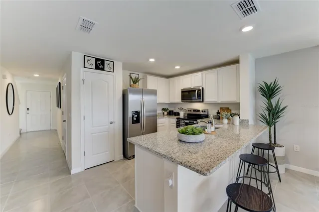 a kitchen with granite countertop stainless steel appliances a sink a counter top space cabinets and center island