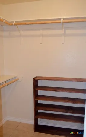 a view of an empty room with chandelier fan