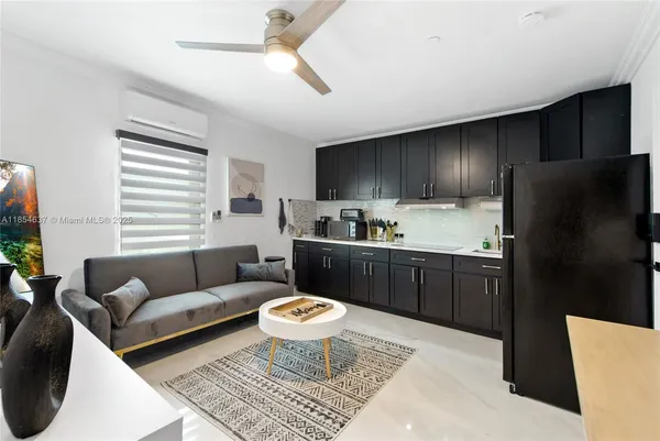 a living room with stainless steel appliances furniture a rug and a window