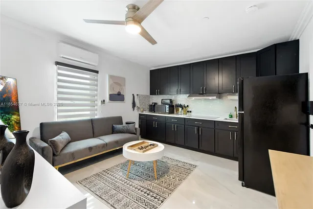 a living room with stainless steel appliances furniture a rug and a window