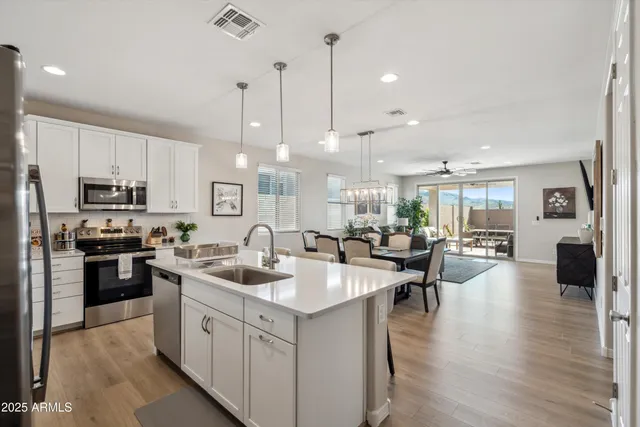 a kitchen with stainless steel appliances granite countertop a refrigerator a sink dishwasher a stove and white cabinets with wooden floor