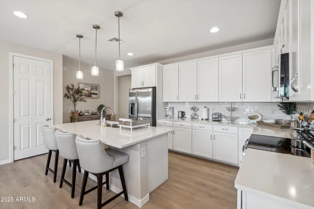 a kitchen with kitchen island a stove a table a sink a refrigerator and cabinets